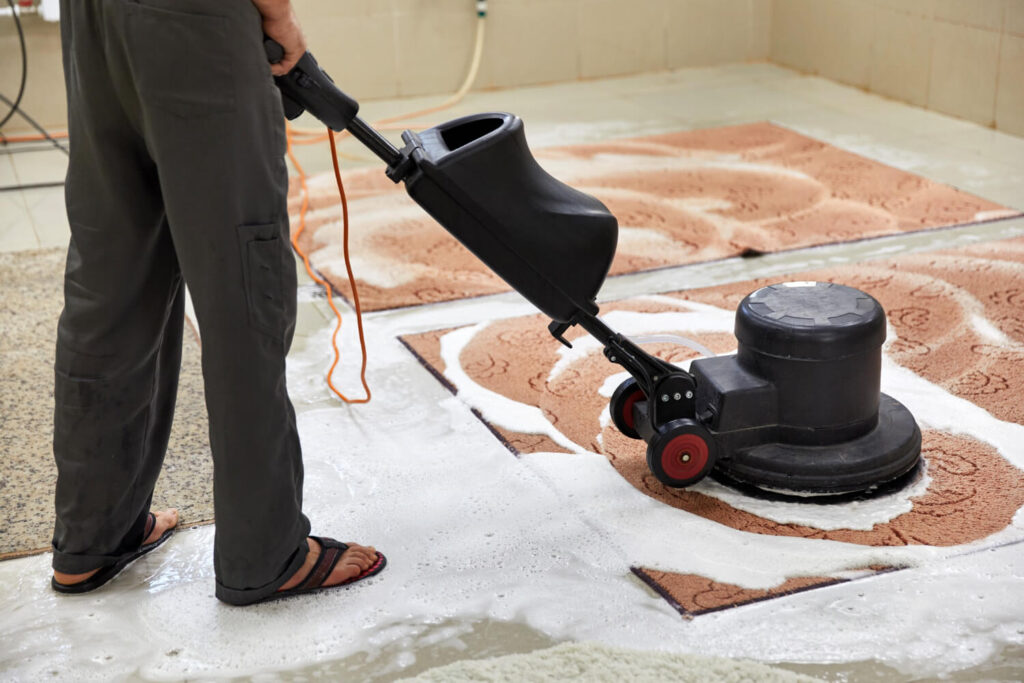 Rotary carpet cleaning machine deep-cleaning a patterned rug